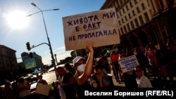 A protester in Sofia against amendments banning LGBT "propaganda" in schools holds up a sign saying, "My life is a fact, not propaganda."