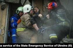 Emergency workers carry a woman rescued from the debris of the devastated apartment block in Dnipro on January 15.