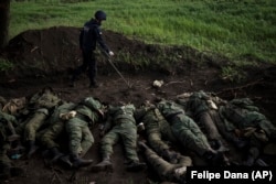 A member of a Ukrainian demining team checks for explosives around the bodies of 11 dead Russian soldiers in the village of Vilkhivka near Kharkiv on May 9. Putin’s decree and the troop increase suggest that the Kremlin is buckling down for a long war in Ukraine.