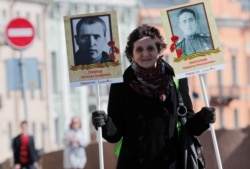 A woman holds portraits of her late relatives as she takes part in the Immortal Regiment memorial event during the celebrations of Victory Day in St. Petersburg.