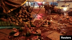 Men look at an overturned car and smashed watermelon stand after a protest in the Biryulyovo district of Moscow on October 13.