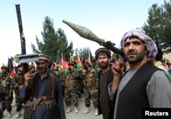 Armed men stand next to Afghan security forces in a show of solidarity against the Taliban, on the outskirts of Kabul on June 23.