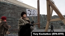 A woman rings a bell made of a rail at the monument to the victims of political repression, the Wall of Grief, as she commemorates victims of political repression in the Soviet Union in Moscow on October 30.