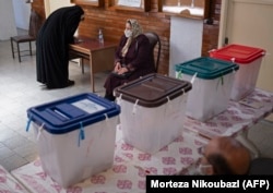 A woman fills out her registration form before voting at a polling station in Tehran on June 18.