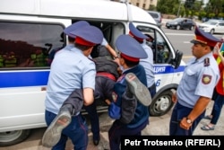 Police bungle a man into a police van in Almaty. June 10, 2019.