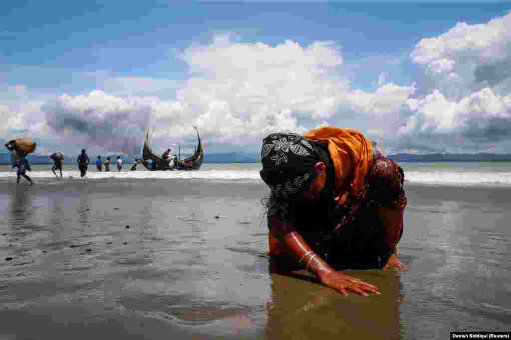 An exhausted Rohingya refugee touches the sand of a Bangladesh beach after fleeing Burma (also known as Myanmar) by boat through the Bay of Bengal on September 11, 2017.&nbsp;