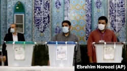 Iranian election officials wait for voters to arrive during the presidential election at a polling station in Tehran on June 18.