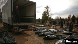 A funeral service employee looks at bodies of civilians, brought from the streets to the local cemetery, in the town of Bucha on April 6.