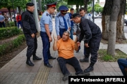 A man sits on the ground as police move to detain him on Almaty's Astana Square. June 10, 2019