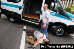 An injured woman lies next to a police vehicle during mass detentions in Almaty. June 10, 2019