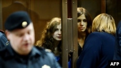 The two members of Pussy Riot whose sentences were upheld, Maria Alyokhina (back left) and Nadezhda Tolokonnikova (back right) speak with a lawyer from a glass-walled cage in a court in Moscow on October 10.