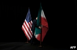 A worker removes Iranian and U.S. flags following a round of talks on Tehran's nuclear program in Vienna in July 2015.