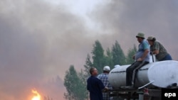 Local residents with a water tank watch as a fire approaches their village of Berestyanki, in the Ryazan region, on August 9.