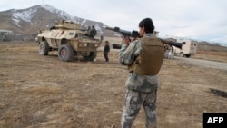 An Afghan security officer holding a rocket-propelled grenade stands at the site of a deadly attack on an army base in Ghazni Province on November 29.