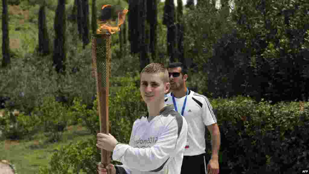 British boxer Alexandros Lucas holds the torch with the Olympic flame during the torch relay after the lighting ceremony in ancient Olympia on May 10, 2012.