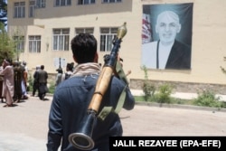 An anti-Taliban militiaman in front of a portrait of Afghan president Ashraf Ghani on June 23.