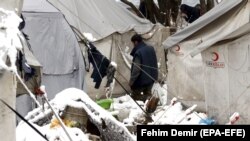 A migrant stands outside a tent on a snowy winter day at the Vucjak refugee camp outside Bihac on December 4.