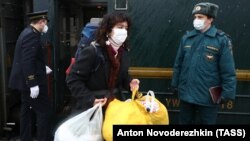 Train attendants wearing protective face masks help passengers leave a Beijing-Moscow train at the Yaroslavsky railway station on February 3.