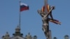 A rainbow ribbon tied to a crucifix is seen next to a Russian flag fluttering atop the State Hermitage Museum during an LGBT rally in St. Petersburg in August.