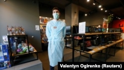 An employee wearing a protective mask and a medical gown as preventive measures against the coronavirus waits for customers at an electronic store in central Kyiv on March 18.